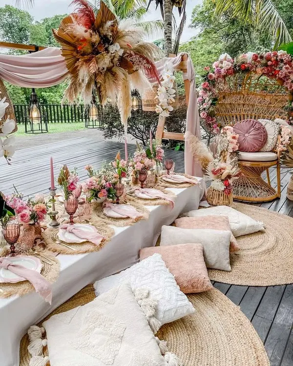 This stunning boho-themed baby shower is perfect for a stylish mom-to-be. The setup includes a peacock chair, low picnic seating with plush cushions, and beautiful dried floral arrangements.