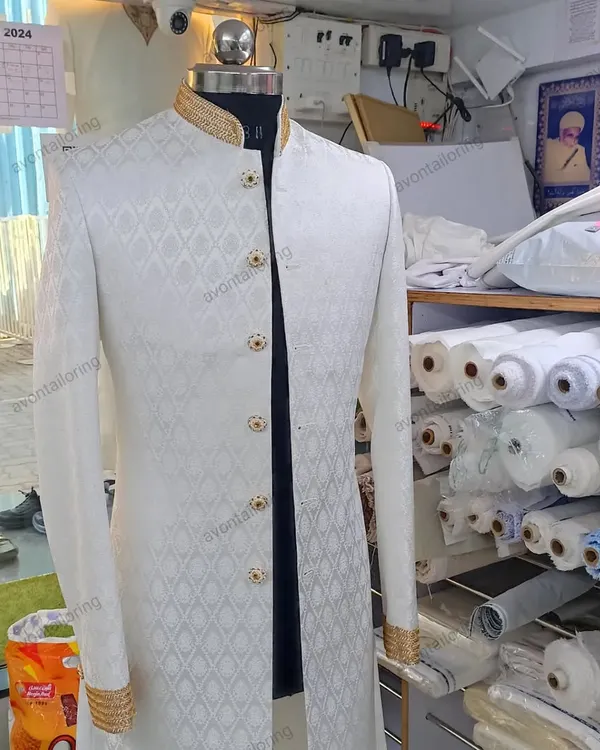 This is a classic wedding sherwani, perfect for a groom who wants a look of timeless elegance. The fabric has a beautiful self-design, and I have added fine zardosi handwork on the collar and cuffs, with matching buttons to complete the look. It's a piece that feels as good as it looks.