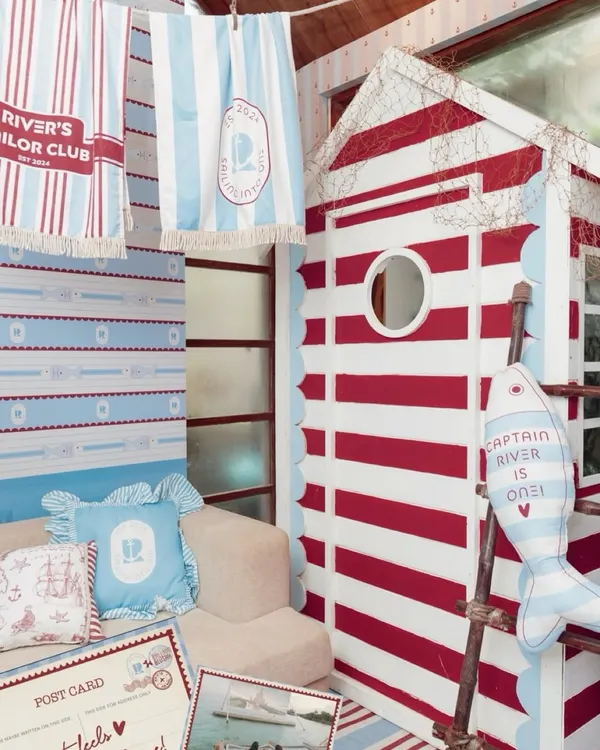 A cozy corner of the "River's Sailor Club" party, featuring a custom-built striped cabin, personalized pillows, and themed towels hanging on a line.