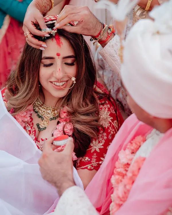 A sacred moment in a Hindu wedding ceremony, as the groom applies sindoor to the bride's forehead, symbolizing their new status as a married couple.