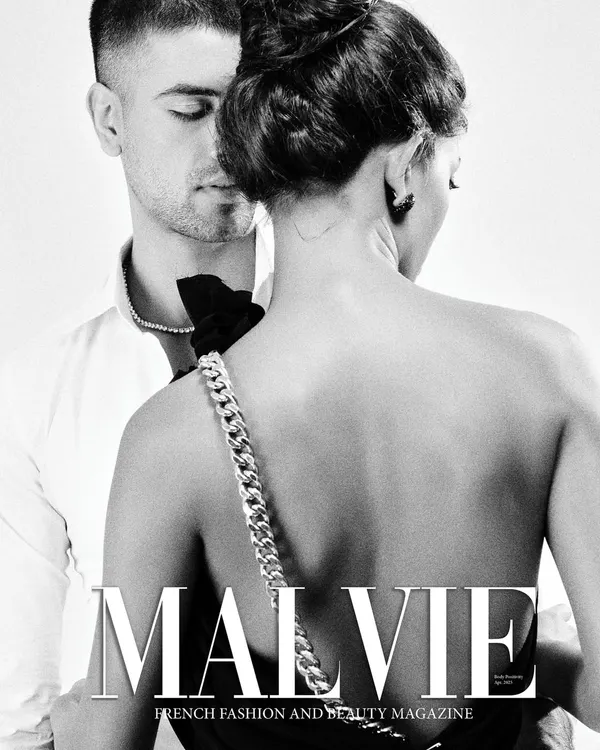 A published cover for Malvie Magazine, this black and white shot captures a quiet, intimate moment. The focus is on the back of the model, highlighting the chain detail of her dress strap, which serves as the central accessory in the frame.