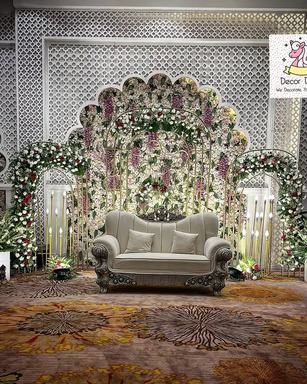 This elegant anniversary stage features a stunning floral backdrop with intricate white latticework and soft lighting. We designed this setup to create a sophisticated and romantic atmosphere for a milestone celebration.