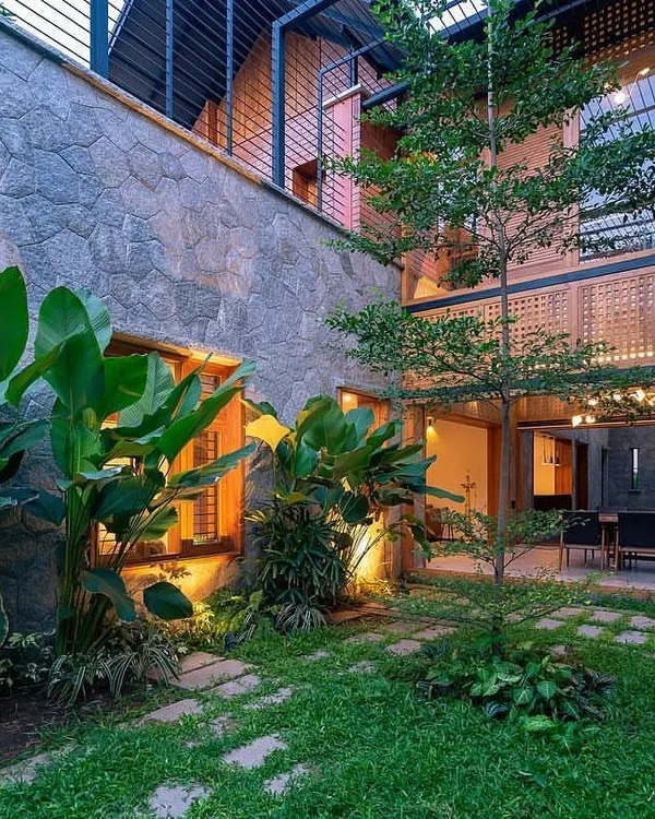 This internal courtyard is designed to be viewed from multiple rooms. It features a mix of natural stone, lush tropical plants like the Bird of Paradise, and a central tree, creating a private, tranquil garden within the home's walls.