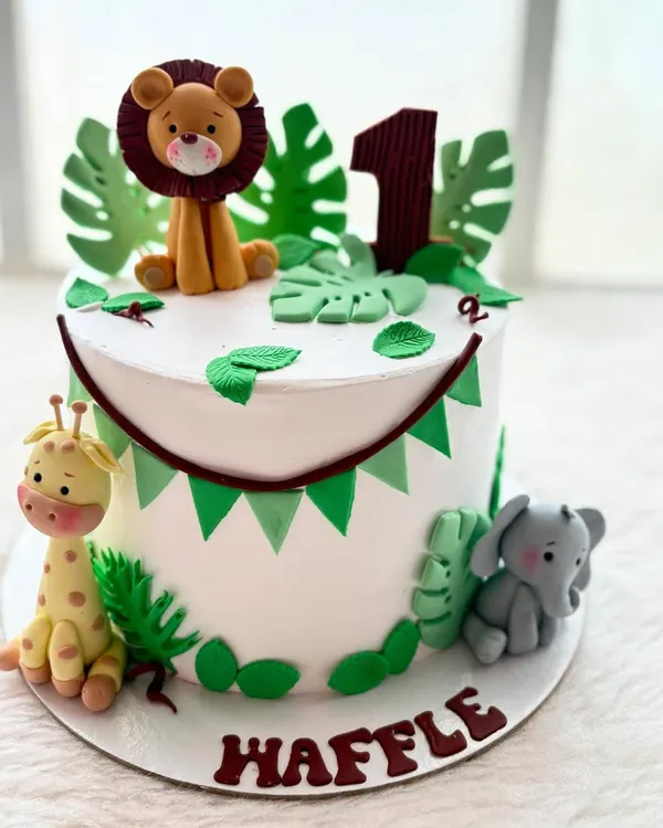 The jungle theme is one of my most popular requests for first birthdays. This cake features adorable, handmade fondant animals like a lion, giraffe, and elephant, surrounded by tropical leaves.