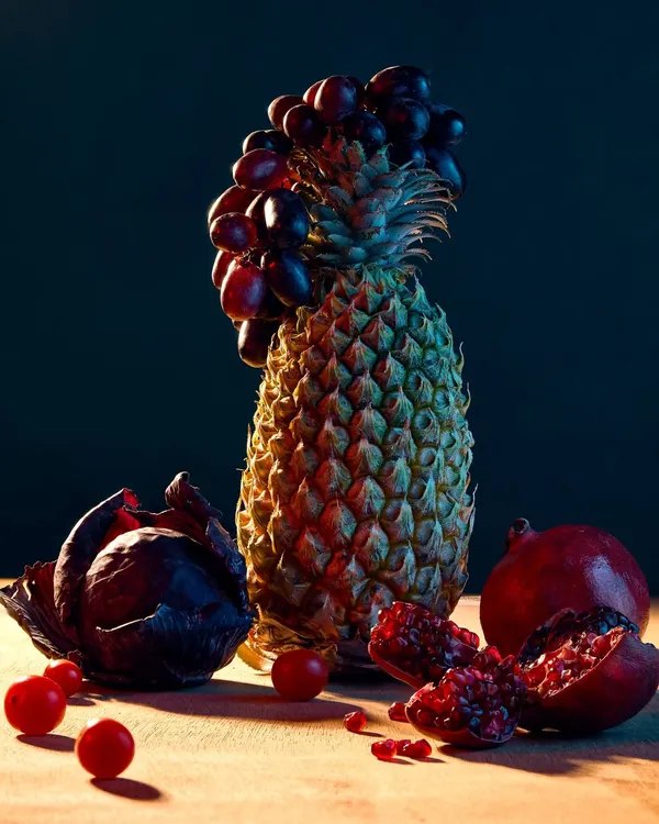Part of my "Fru-Veg" series, this image is a creative still life experimenting with light and form. I constructed a sculpture using a pineapple, grapes, and a purple cabbage, using dramatic lighting to create a painterly effect.