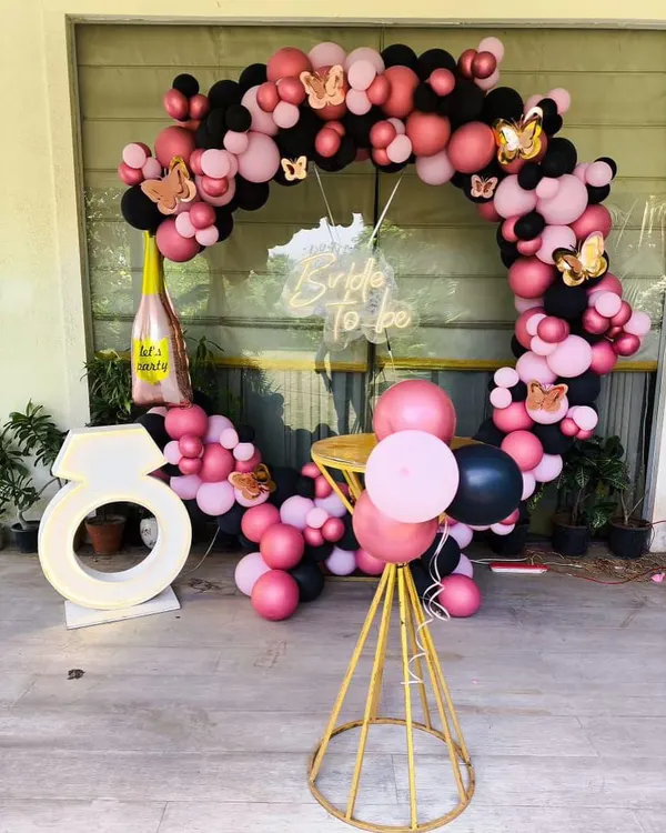 For this bride-to-be party, I created a full circular balloon arch in pink and black, accented with gold butterflies. The setup includes a custom 'Bride To be' neon sign and a large, illuminated ring prop for the perfect photo opportunity.