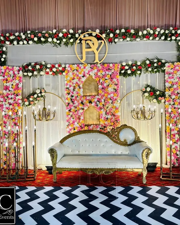 This is where your forever begins. I designed this wedding stage with a magnificent wall of pink and white florals, elegant candelabras, and a classic white and gold sofa to create a truly royal setting for the couple's big day.