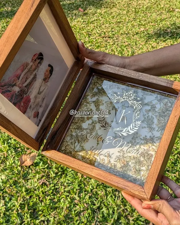 This is my folding teak wood box frame, a truly unique way to preserve your memories. One side holds a photo, and the other holds your wedding flowers preserved in resin with a custom monogram.