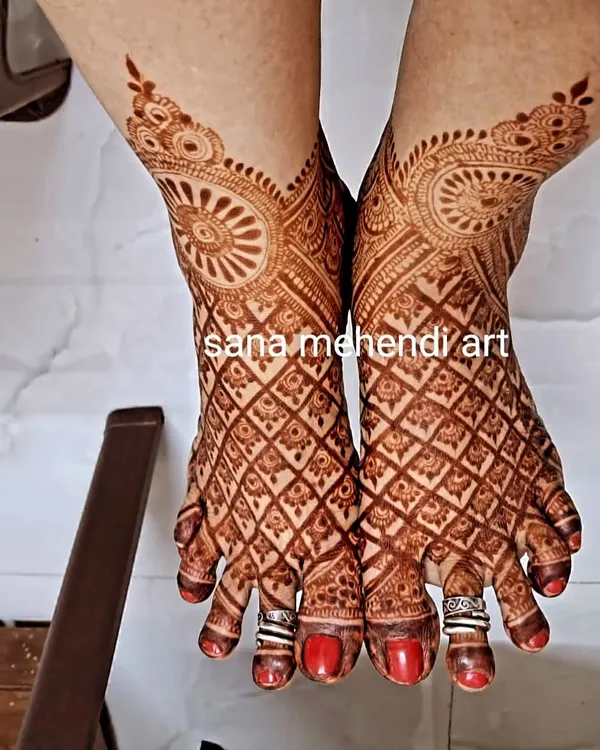 A full bridal foot mehendi with a rich, dark stain. The design features a detailed net pattern covering the entire foot.