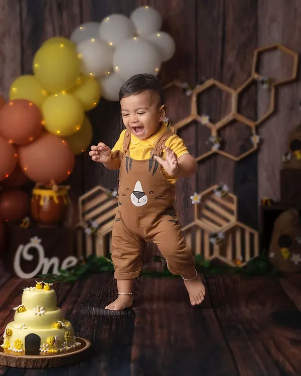 Little hands, big dreams, and an even bigger leap of joy! This little one can't wait to get his hands on that yummy bee-themed cake.