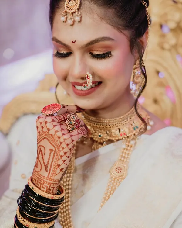 A detailed shot of the bride's hands, adorned with intricate mehndi and the groom's initial. This portrait highlights the beautiful jewelry and the traditional black bangles, capturing the essence of a Maharashtrian bride.