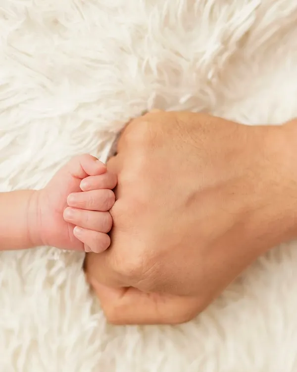 A newborn's tiny fist bumping their parent's. This powerful image symbolizes the immediate and strong connection between a parent and child.