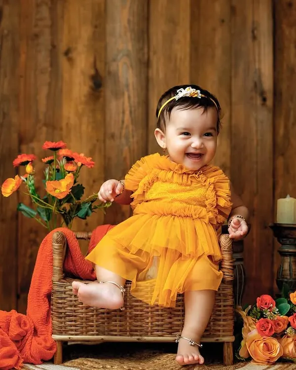 I love this warm, rustic setup. The rich tones of the wooden background and the bright orange dress make this little one's joyful smile pop.