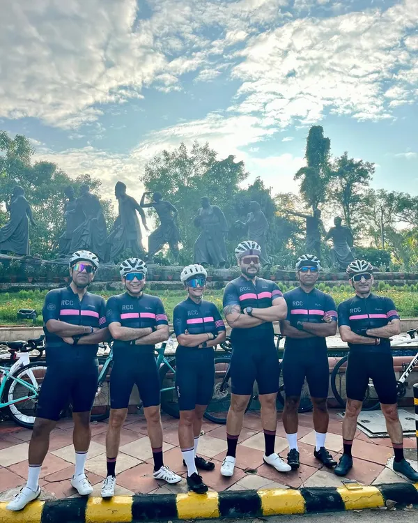 The team lines up in matching kits to celebrate a member's birthday ride. The Gyarah Murti statue provides a powerful backdrop for our group photo.