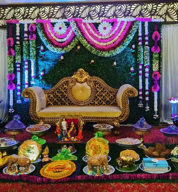 This is a complete Seemantham setup, one of our most requested services. It features a lush greenery backdrop with floral garlands, an ornate golden sofa for the mother-to-be, and a full display of our signature decorated thamboolam plates.