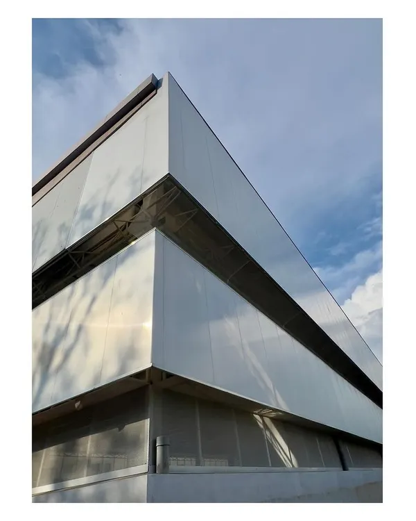 The exterior of an industrial project under construction, featuring polycarbonate and metal wall panels. The design focuses on creating a clean, efficient, and light-filled factory environment.