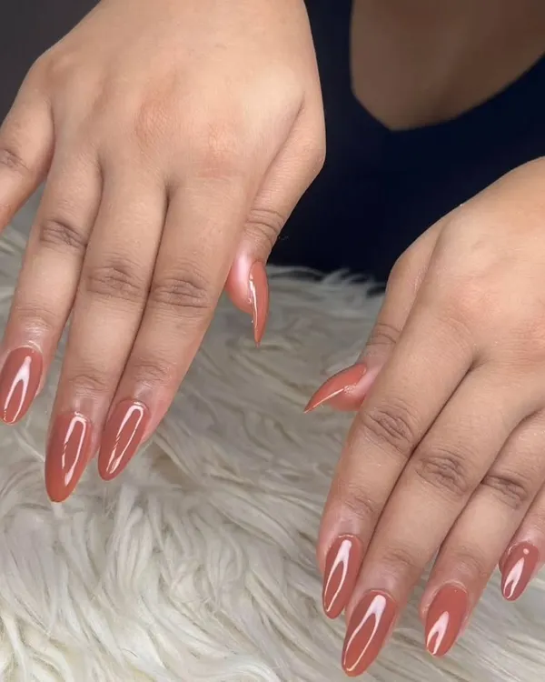 A full view of the glossy terracotta gel polish on long, almond-shaped extensions, showcasing their consistent shape and flawless application.