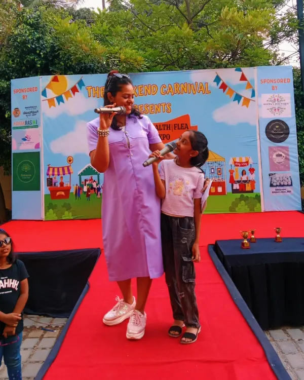 On stage at "The Weekend Carnival," sharing the mic with a confident young participant. I enjoy hosting community events that bring families and local talent together.