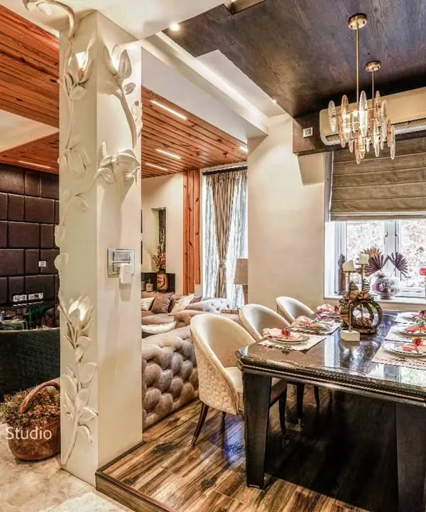 An open-plan living and dining area where a custom-carved pillar elegantly separates the two zones, showcasing a blend of rich textures and luxurious details.