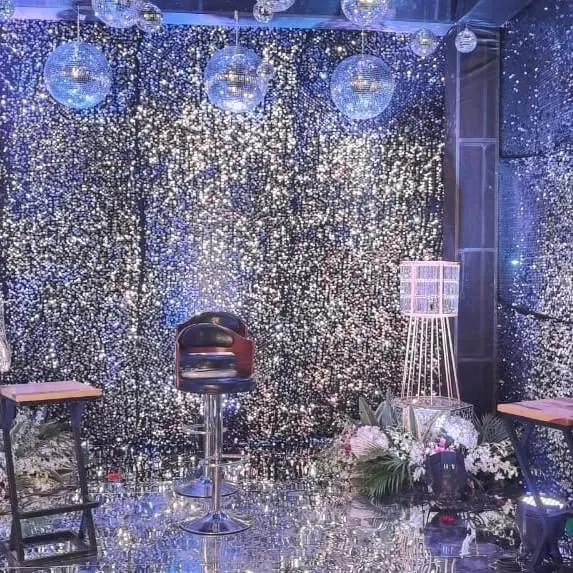 A fully immersive party environment created with silver shimmer walls on all sides and a reflective floor. The space is accented with hanging disco balls, creating a dazzling effect that's perfect for a dance party or cocktail event.