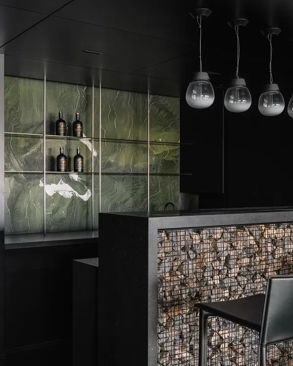 We conceptualized this bar for the Vaulted Haus project as part of a larger architectural gesture. The facia is a custom Gabion wall, created by trapping randomly sized stones in a metal wire mesh, introducing a raw, textural element that contrasts with the sleek, black PU-coated surfaces of the surrounding space.