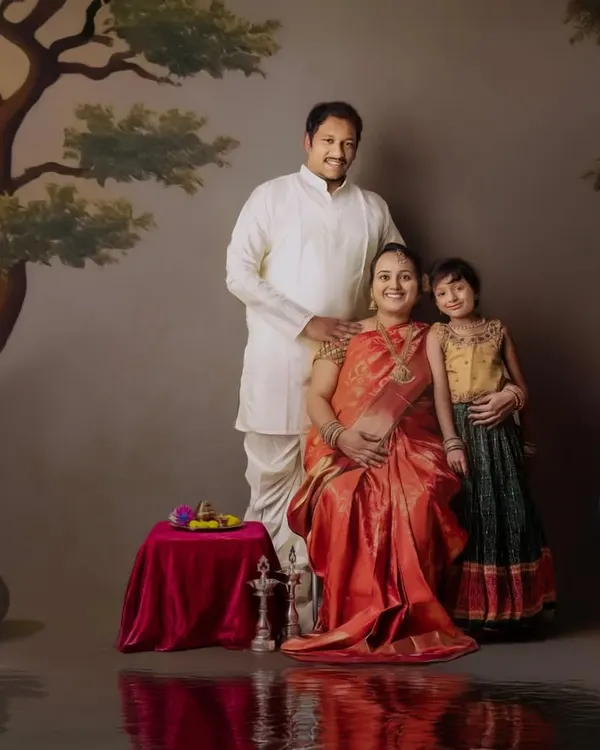 A regal family maternity portrait. The expecting mother is seated like royalty, surrounded by her family in a beautifully painted, traditional Indian setting.