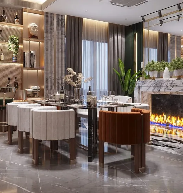 A view of the dining and bar area from our Sushant Lok project. We designed this space for entertaining, with a custom bar, an elegant dining set, and a modern fireplace feature. The material palette of marble, wood, and metal, combined with lush greenery, creates a sophisticated and welcoming atmosphere.