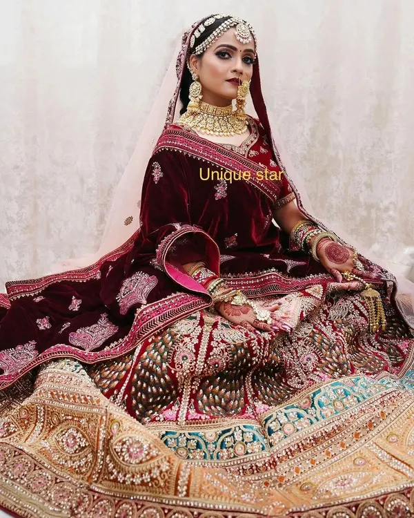 A classic bridal masterpiece. This velvet maroon and multi-panel lehenga with heavy zardozi and stone work is designed for the bride who wants a truly royal and traditional wedding day look.