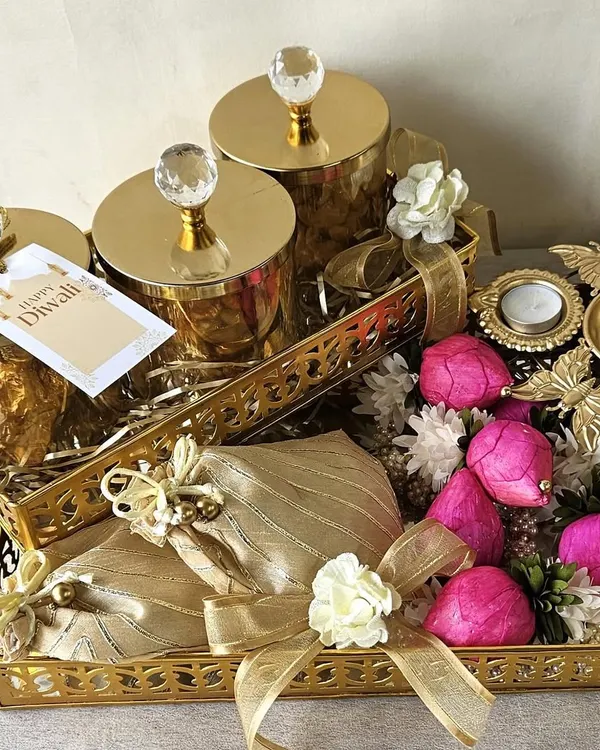 A truly grand gesture for Diwali, this hamper features golden trays laden with crystal-topped jars, festive potlis, and decorative flowers. It’s a luxurious gift designed to impress and delight your most cherished connections.