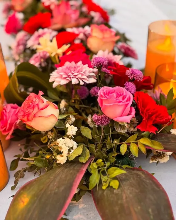 A close-up of a vibrant floral centerpiece surrounded by warm candlelight. These small arrangements on guest tables add color and elegance to the overall reception decor.