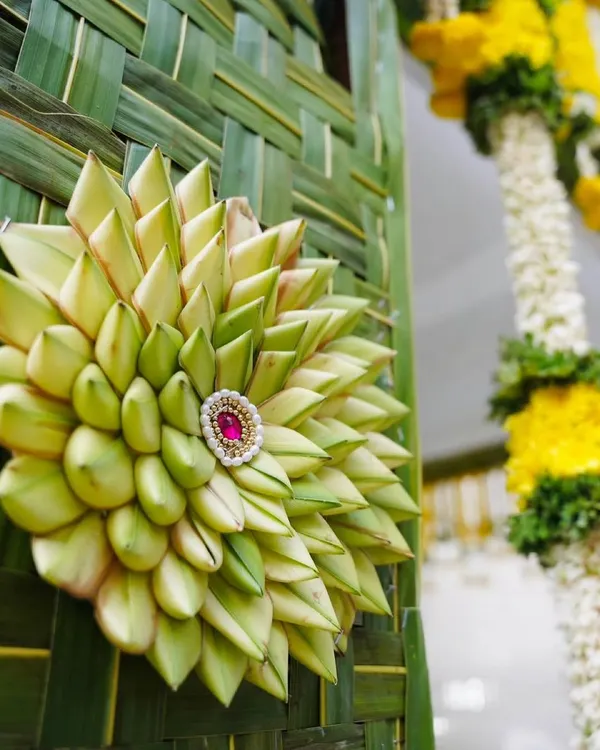 A close-up of a 'chapra' wall medallion. In our workshops, you'll learn this intricate art of folding and weaving tender coconut leaves, a hallmark of authentic traditional South Indian decor.