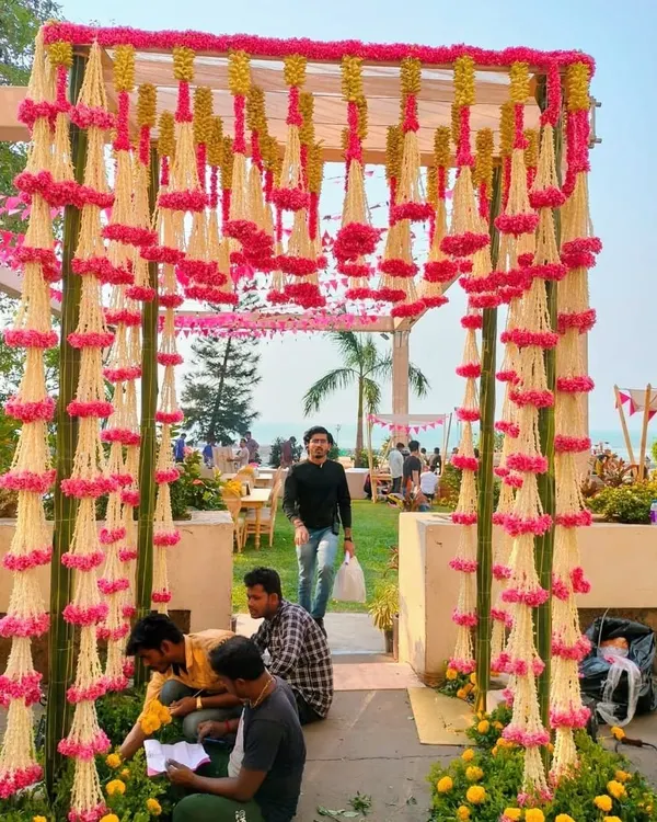 For this destination wedding, we created a stunning floral entryway with hanging garlands of pink and white flowers. Our team is on-site to ensure every petal is perfectly in place for the grand entrance.