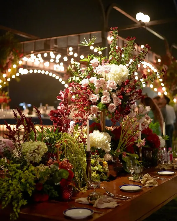 A stunningly opulent tablescape featuring a symphony of lush florals in deep reds and soft pinks. The warm glow of candles and gold accents brought an old-world charm to this enchanting dinner setting.