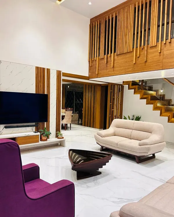 We designed this double-height living room to feel both grand and welcoming. The combination of warm wood paneling, sleek marble flooring, and a dramatic staircase creates a space that is perfect for both relaxing and entertaining.