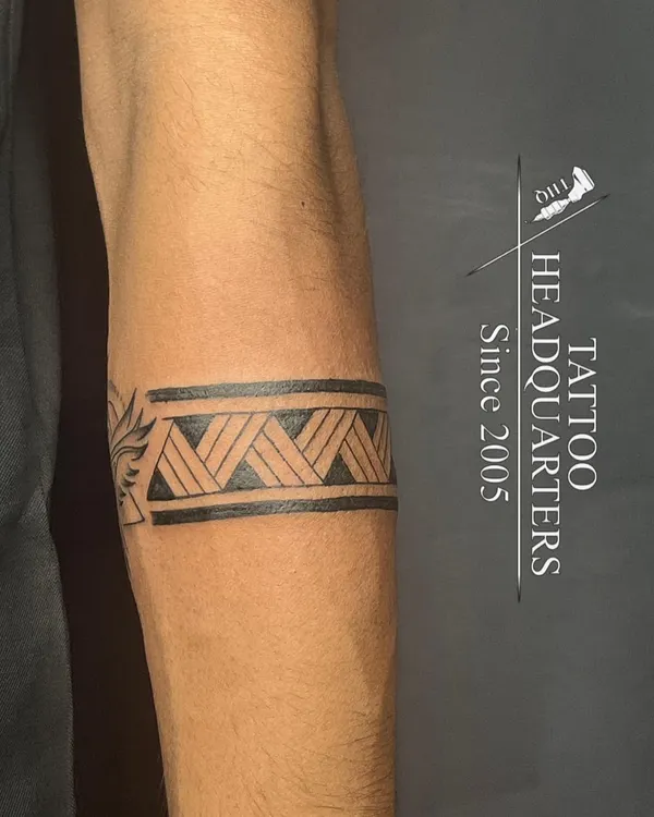 A classic tribal armband tattoo with a woven pattern, showcasing clean lines and solid black fill.
