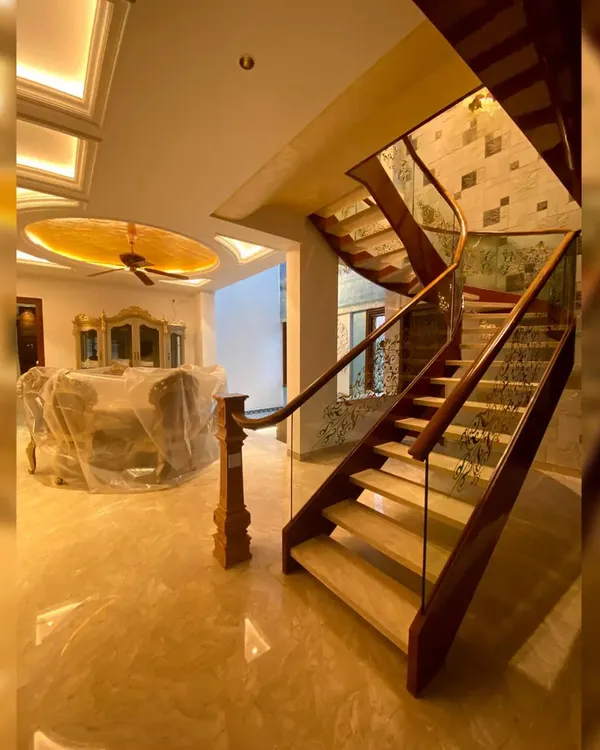 A view of a grand, open staircase we designed for a luxury duplex residence in Bengaluru. The combination of polished wood, glass railings, and marble flooring creates an immediate sense of opulence, while the intricate ceiling design adds another layer of custom detail.