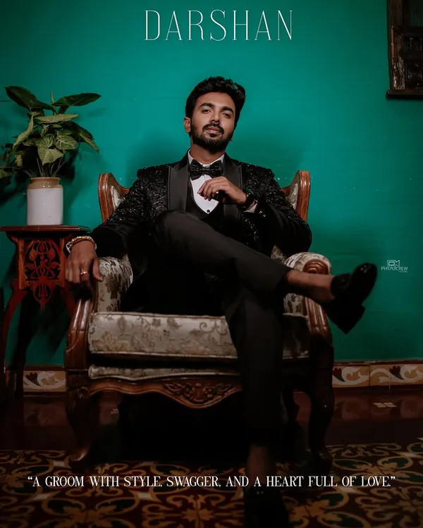 A stylish portrait of the groom seated in a vintage chair, looking sharp in his reception tuxedo.