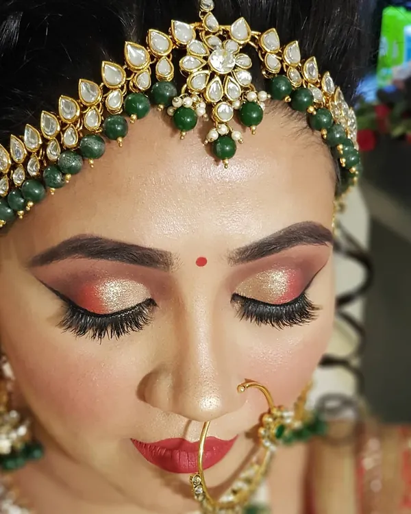 A detailed close-up of a bridal cut crease. I used warm red and shimmering gold eyeshadows with a sharp wing to create a dramatic and defined look that perfectly complements a traditional Indian bridal outfit.