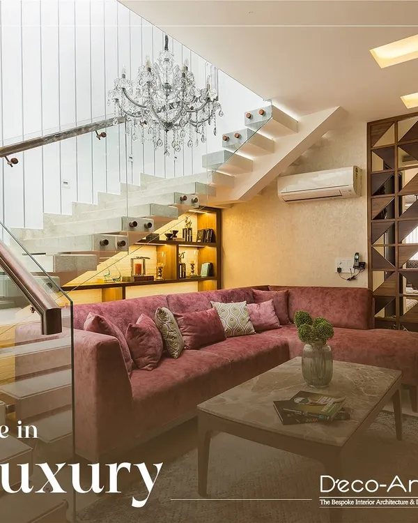 Experience the perfect blend of modern elegance and timeless charm. This living room under a floating staircase uses a plush velvet sofa and a grand chandelier to create a space that is both luxurious and inviting.