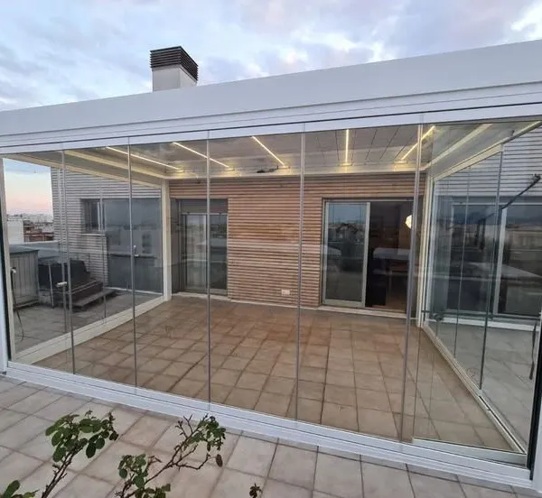 A complete rooftop sunroom constructed with sliding glass panels and a fixed glass roof. This enclosure creates a usable, light-filled room on the terrace, protected from wind and rain.