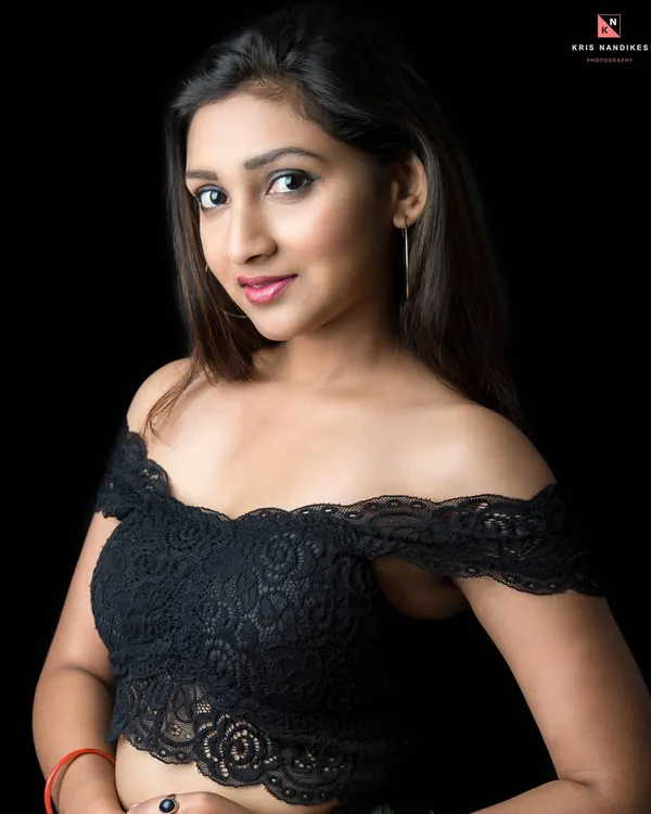 A simple yet effective portrait using low-key lighting. The focus is entirely on the model's face and expression, with the off-shoulder lace top adding a touch of style. This is a great example of a clean, modern headshot.