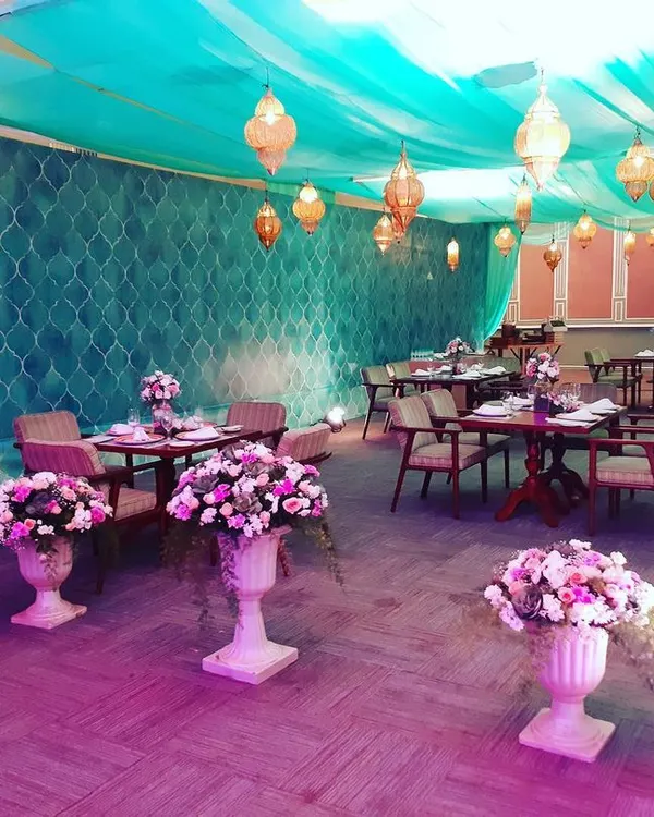 We create immersive environments for your guests. This dining area features Moroccan-style lanterns, elegant floral urns, and beautiful teal drapery to set a unique and intimate mood for a reception or party.