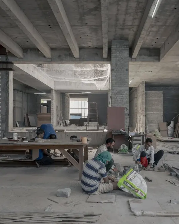 The Courtyard House in Hyderabad during construction. It's a moment of organized chaos as craftspeople work on the flooring, bringing the raw concrete structure to life.