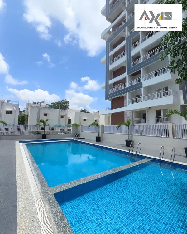 This is a ground-level view of the apartment complex pool, showing the crisp, clean finish. The dual-level design, with a shallow area for lounging or for children, adds functionality. The simple, durable materials used for the pool deck ensure longevity and a timeless modern look.