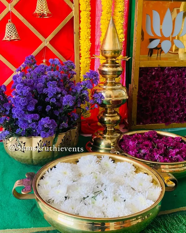 A close-up of our pooja area decor. We use traditional brass urlis and bowls filled with fresh flowers like chrysanthemums and daisies, alongside shining brass lamps, to create a truly divine space.