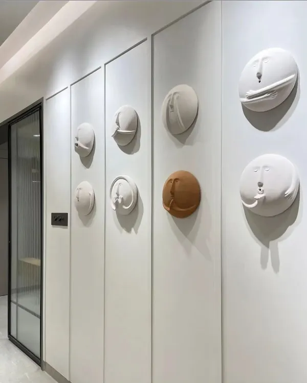 Art can be integrated directly into your walls. This hallway features a unique installation of quirky, 3D clay faces, turning a simple passage into a gallery of conversation-starting art.