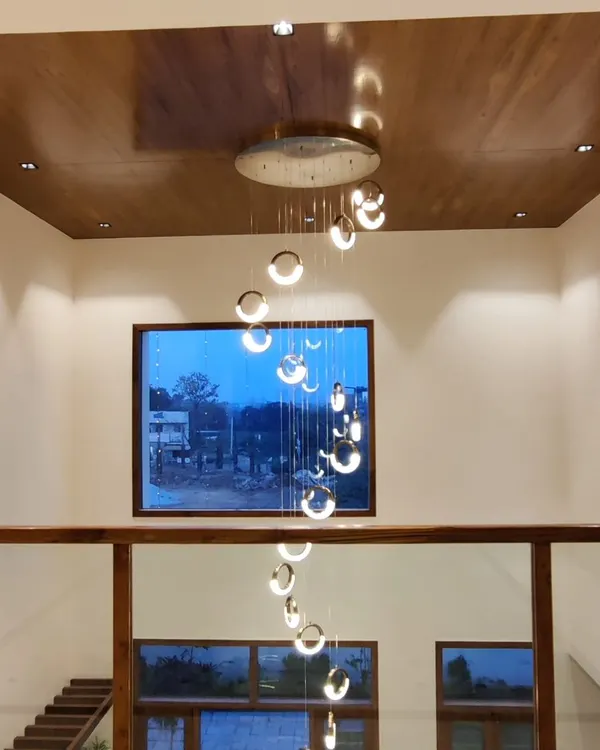 This cascading spiral chandelier creates a stunning focal point in a double-height entryway. The fixture descends through the space, providing light to both levels and adding a sense of drama.