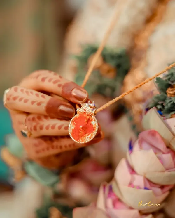 A close-up of the bride holding the sacred thali or mangalsutra. This shot highlights a deeply symbolic and emotional part of the wedding ceremony.