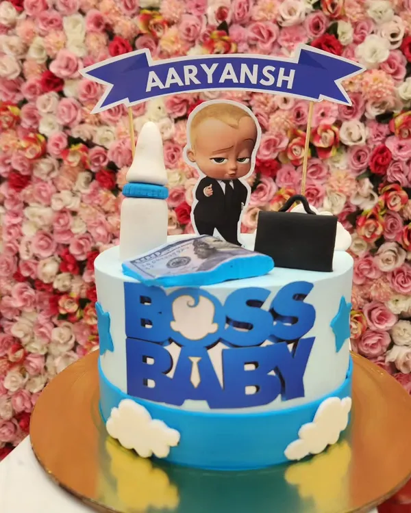 A classic Boss Baby cake perfect for a first birthday. This design features a personalized banner and fondant details like a milk bottle and briefcase, capturing the fun theme for your little one.