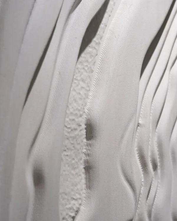 A detailed view of a sculptural wall panel, showing the interplay of smooth and rough textures. I designed this to capture the feeling of natural, flowing movement in solid stone.